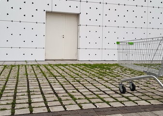 An empty grocery basket is on the street near the supermarket