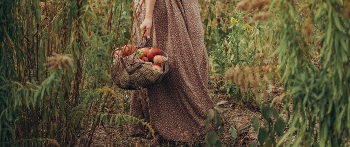 Na zdjęciu jest kobieta trzymająca kosz z płodami rolnymi.